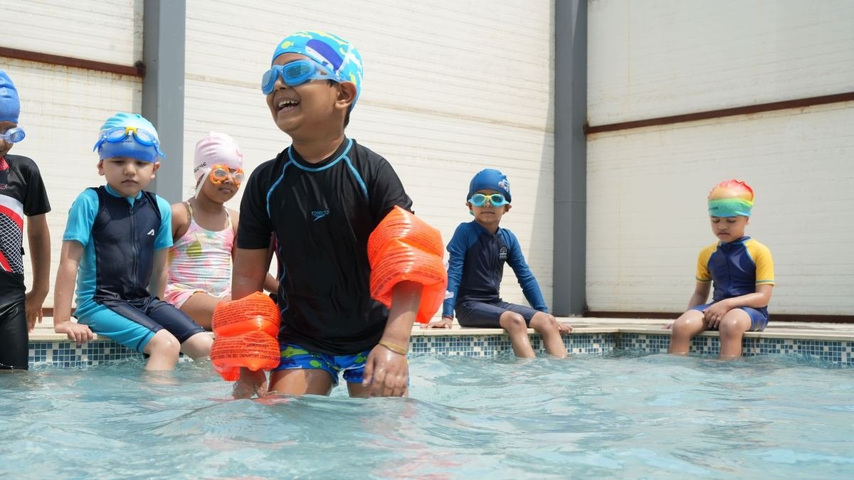Early years students learning to swim with floats in the school pool
