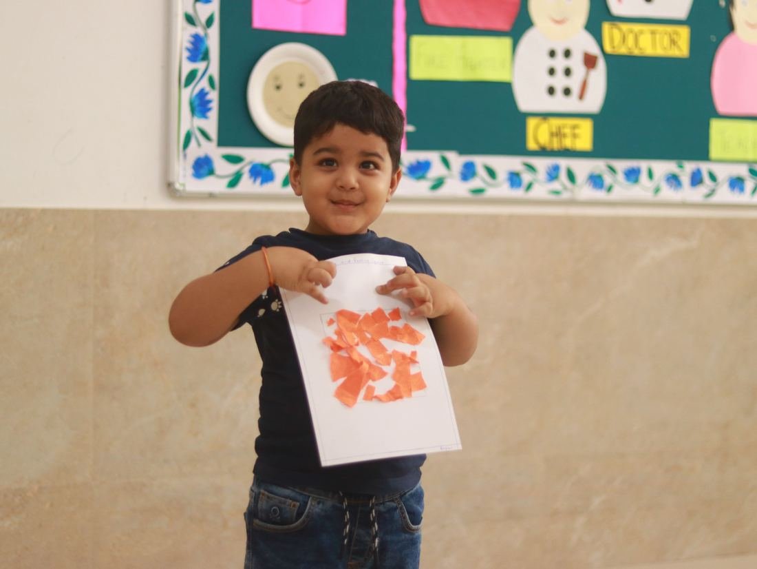 Nursery student proudly showing an art activity in the classroom